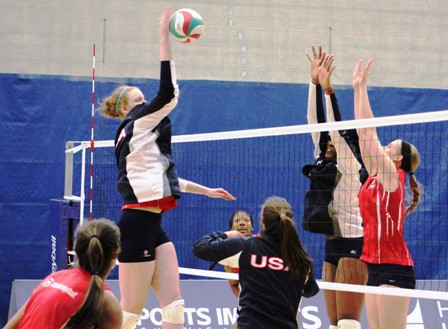 Katie Slay hitting over blockers in a demonstration my members of the USA Volleyball Women's National Team.